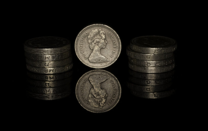 Pound coins reflected on black