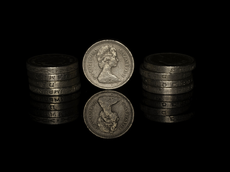Pound coins reflected on black